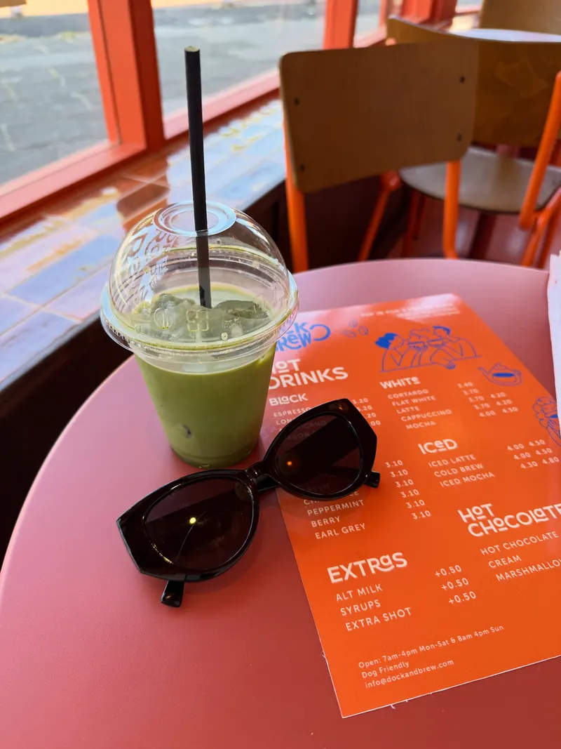 An iced matcha on a pink table by the window